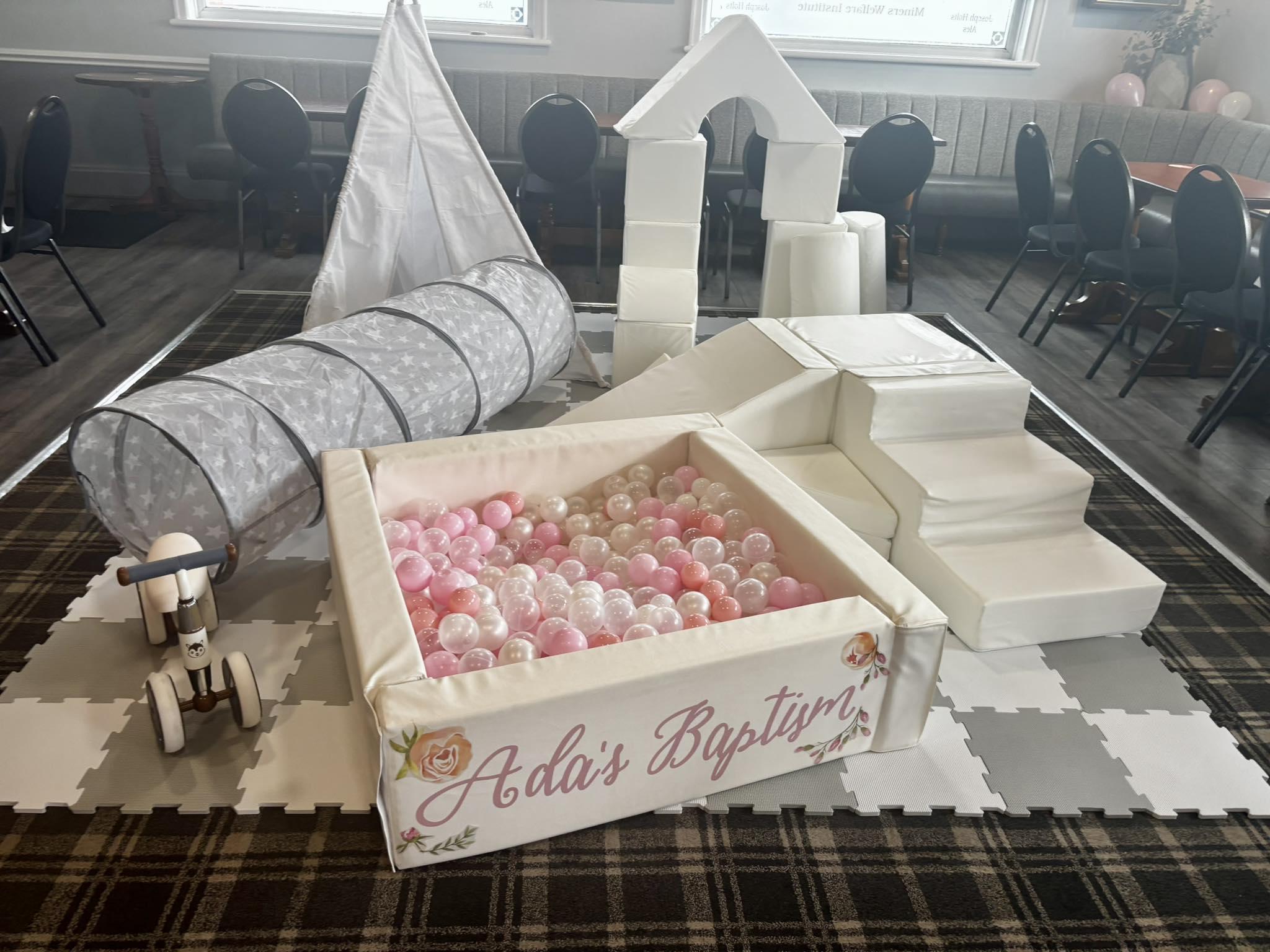 Soft play setup with pink and pearl ball pit and personalised signage